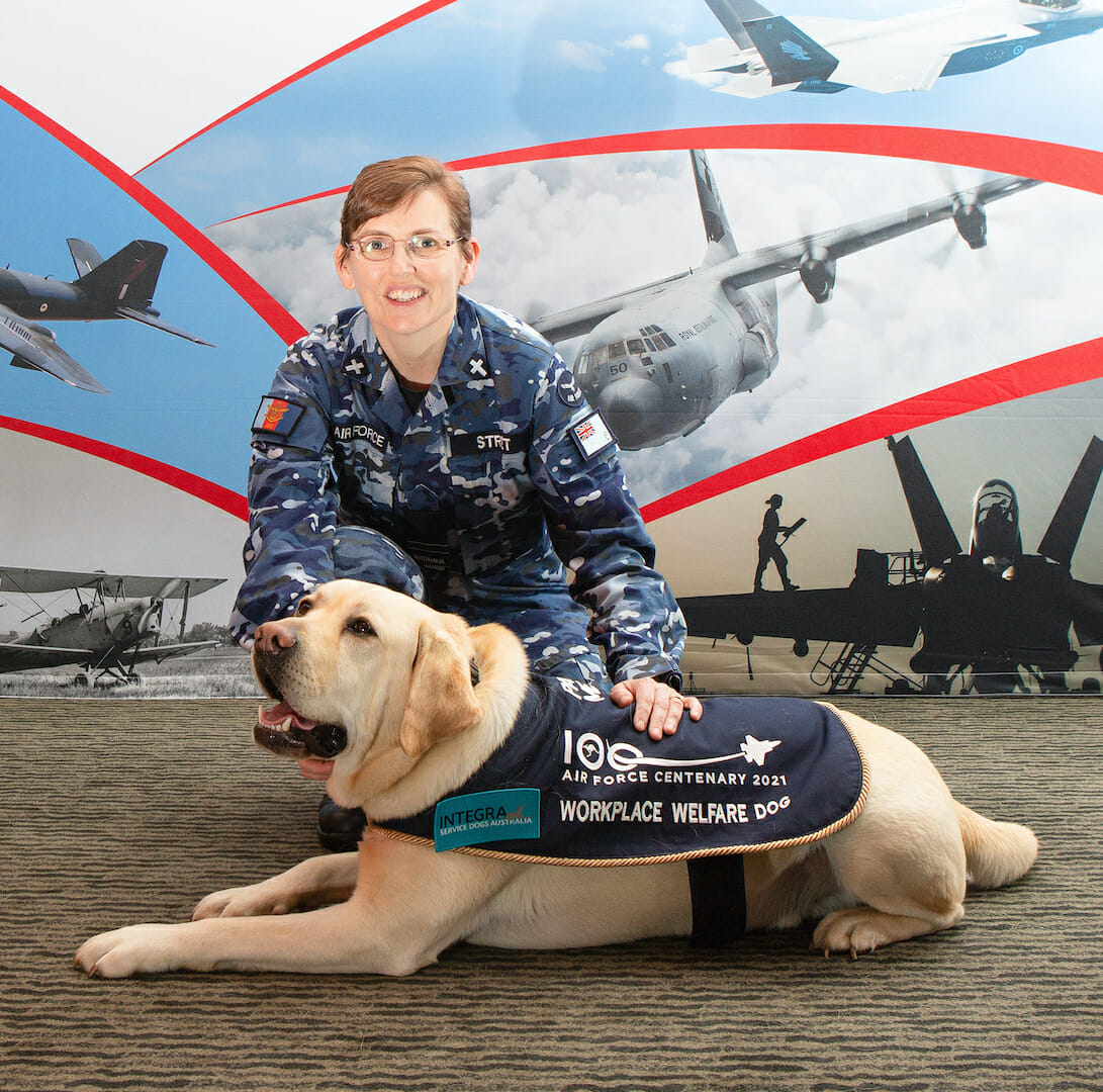 Image of Hooper, the Workplace Welfare Dog, receives a pat from Chaplain Emma Street during Hooper's visit to Air Force 2021 at RAAF Base Fairbairn, ACT.